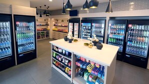 A modern retail space with refrigerated beverage dispensers, shelves stocked with snacks, and a central island with decorative items. - Hyatt Regency Los Angeles International Airport (Los Angeles)