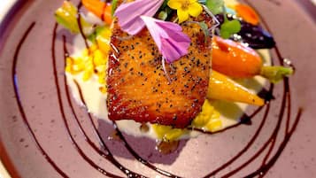 A plate with a piece of salmon, vegetables, and a decorative flower arrangement.