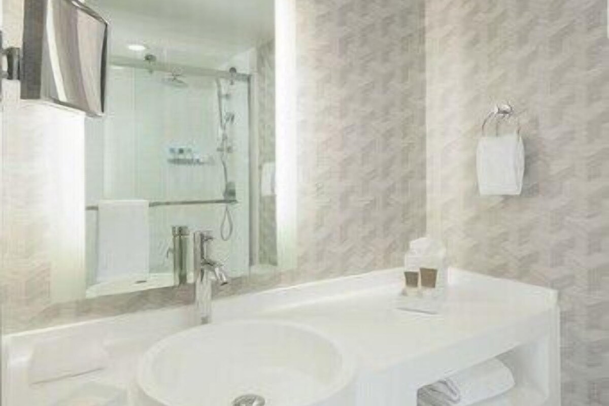 Un baño moderno con un lavamanos grande, un espejo y un perchero para toallas.