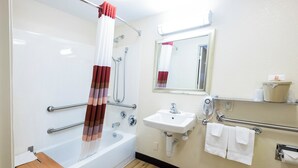 Un baño con bañera, ducha, lavabo, espejo y toallero.