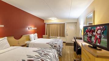 A hotel room with two beds, a television, a desk, and a mirror.