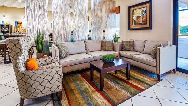 Una sala moderna con un sofá seccional, un sillón estampado y una mesa de centro.