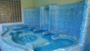 Tinaja con mosaicos y diseño circular en el centro, rodeada de escalones y paredes.