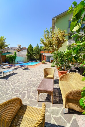 A poolside area with wicker furniture, a pool, and potted plants. - HG Hotel Cappelli (Montecatini Terme)