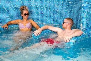A pool with tiled walls and two people relaxing in the water. - HG Hotel Cappelli (Montecatini Terme)