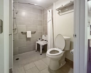 A bathroom with a toilet, shower, and a small step stool.