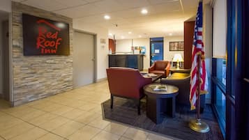A Red Roof Inn lobby with a reception desk, seating area, and an American flag.