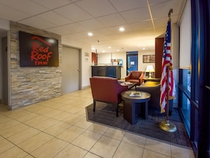 Un vestíbulo de Red Roof Inn con una recepción, zona de estar y una bandera estadounidense.