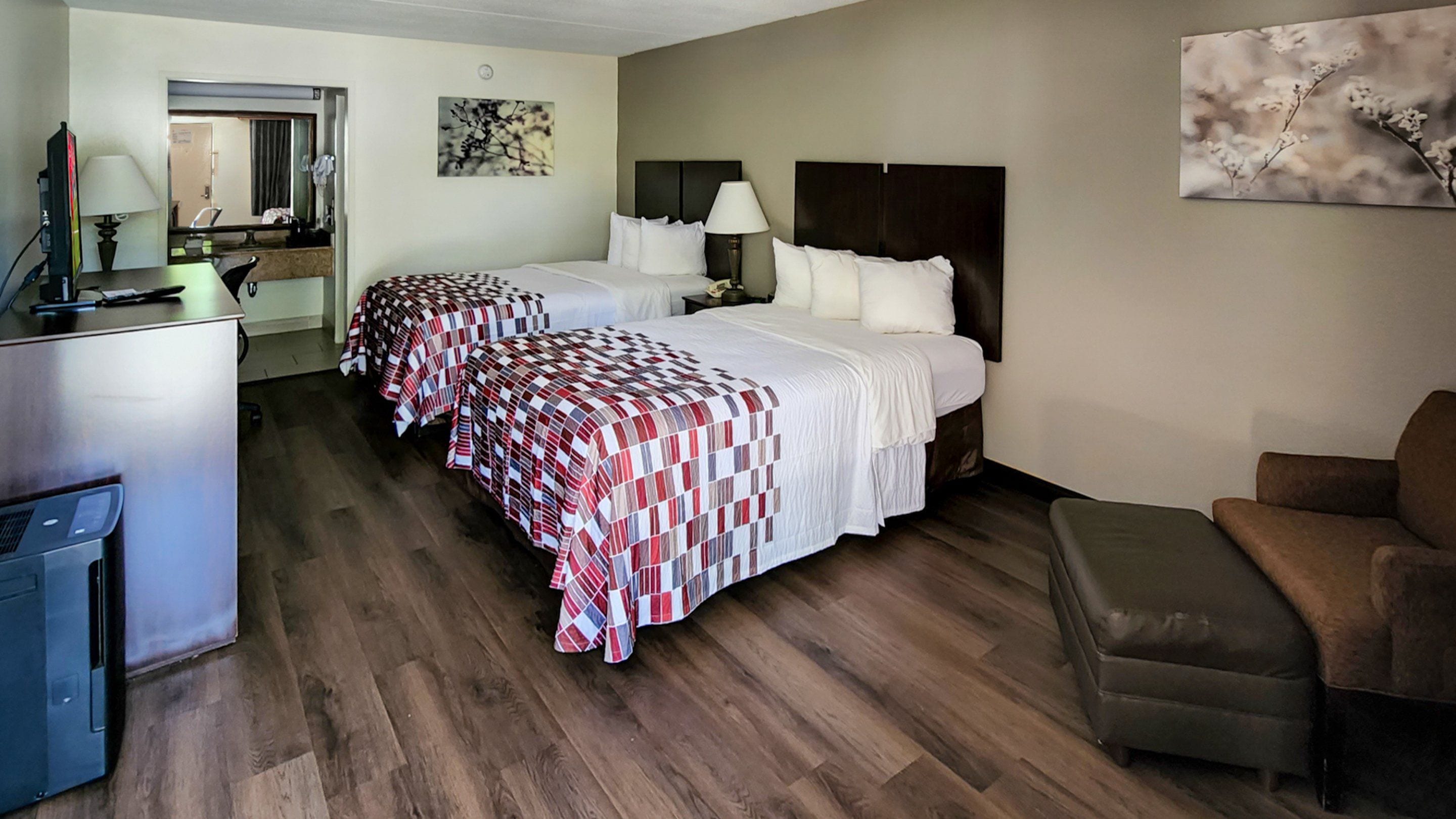 Habitación de hotel con dos camas, un escritorio, una silla y un sofá.