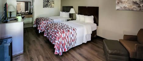 A hotel room with two beds, a desk, a chair, and a couch.