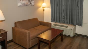 A room with a brown sofa, a wooden table, a lamp, and an air conditioning unit.