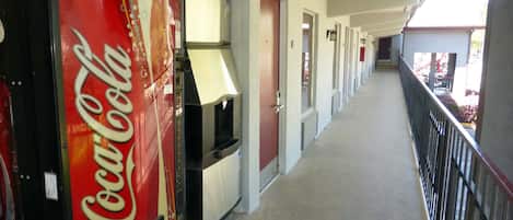 A corridor with vending machines, doors, and a railing.