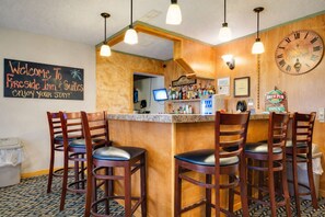 A bar area with wooden chairs, a clock, and a sign reading 'Welcome to Fireside Inn & Suites Enjoy your stay!'