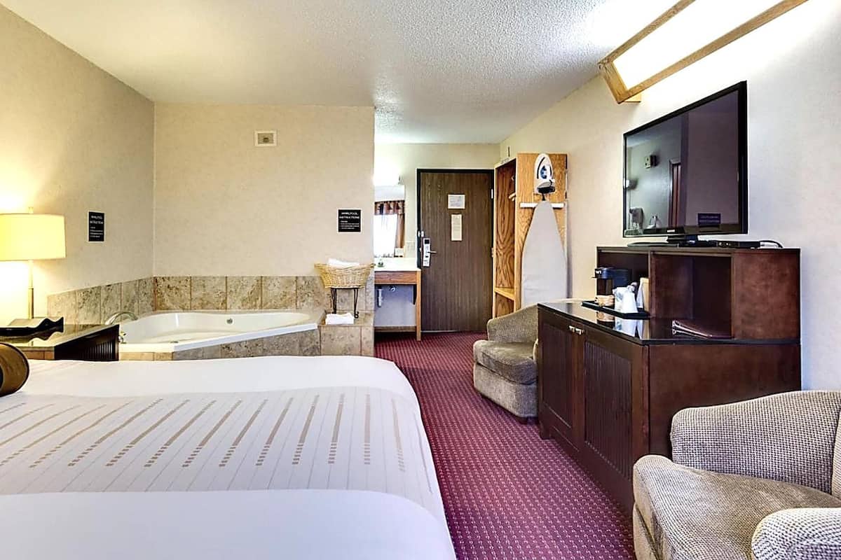 A hotel room with a bed, a desk, a chair, a television, and a bathroom with a bathtub.