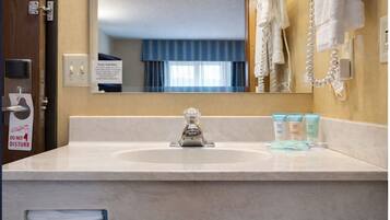 A hotel bathroom with a sink, mirror, towel rack, and toiletries.