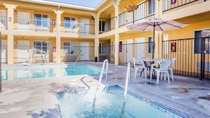 A swimming pool with a diving board, surrounded by white plastic chairs and a table. - Econo Lodge Inn & Suites Lodi - Wine Country Area (Lodi)