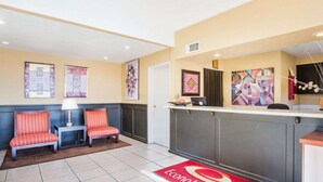 A reception area with a desk, two chairs, and a red carpet with the logo. - Econo Lodge Inn & Suites Lodi - Wine Country Area (Lodi)
