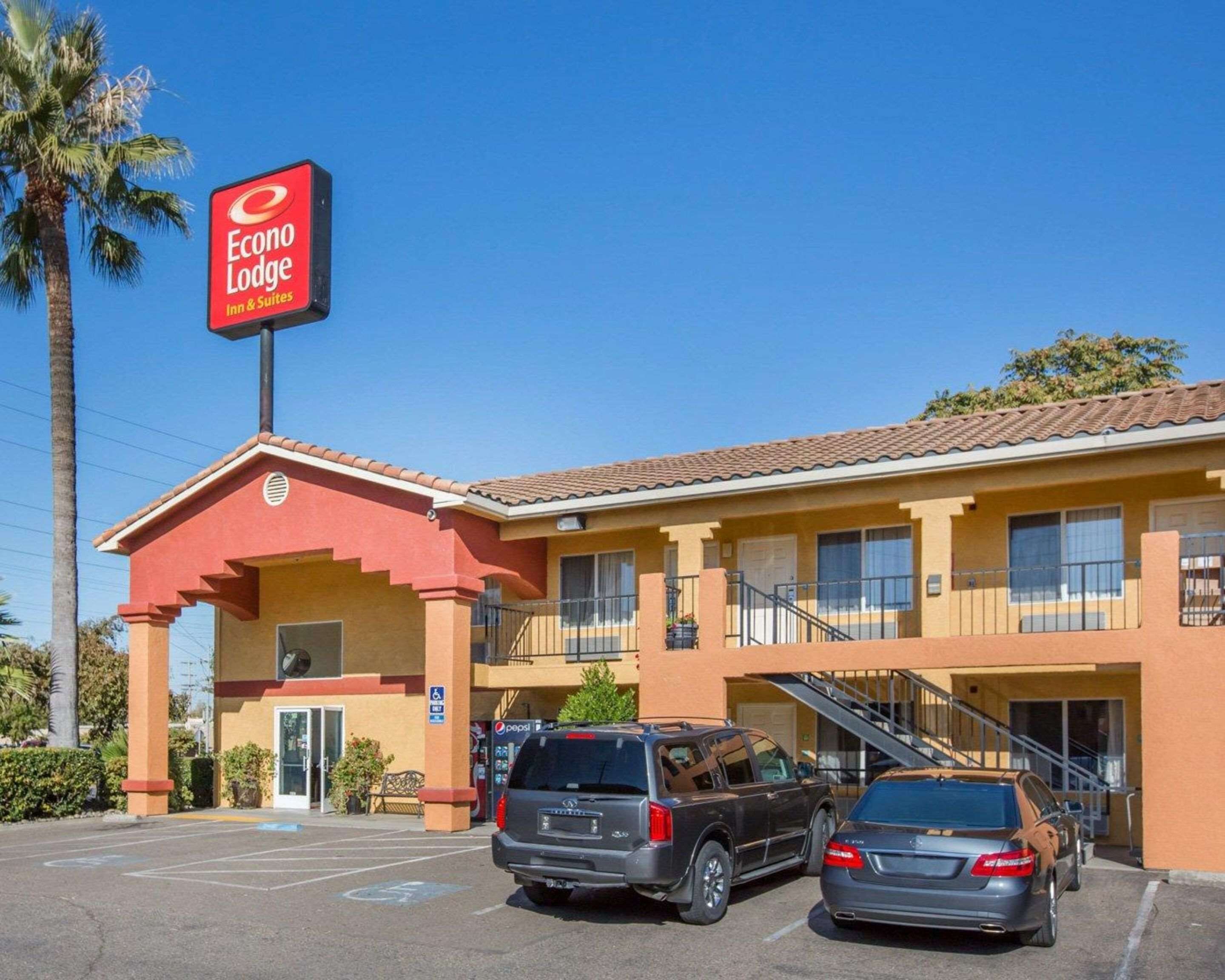 Ein Motel mit roter und gelber Fassade, einem Pepsi-Schild und zwei parkenden Autos.