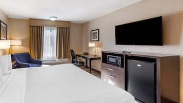 Una habitación de hotel con una cama grande, un escritorio con una computadora, un televisor y un microondas.