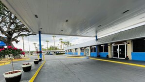 Una estación de servicio con una zona de aparcamiento techada, surtidores de combustible y un edificio de paredes exteriores azules y blancas.