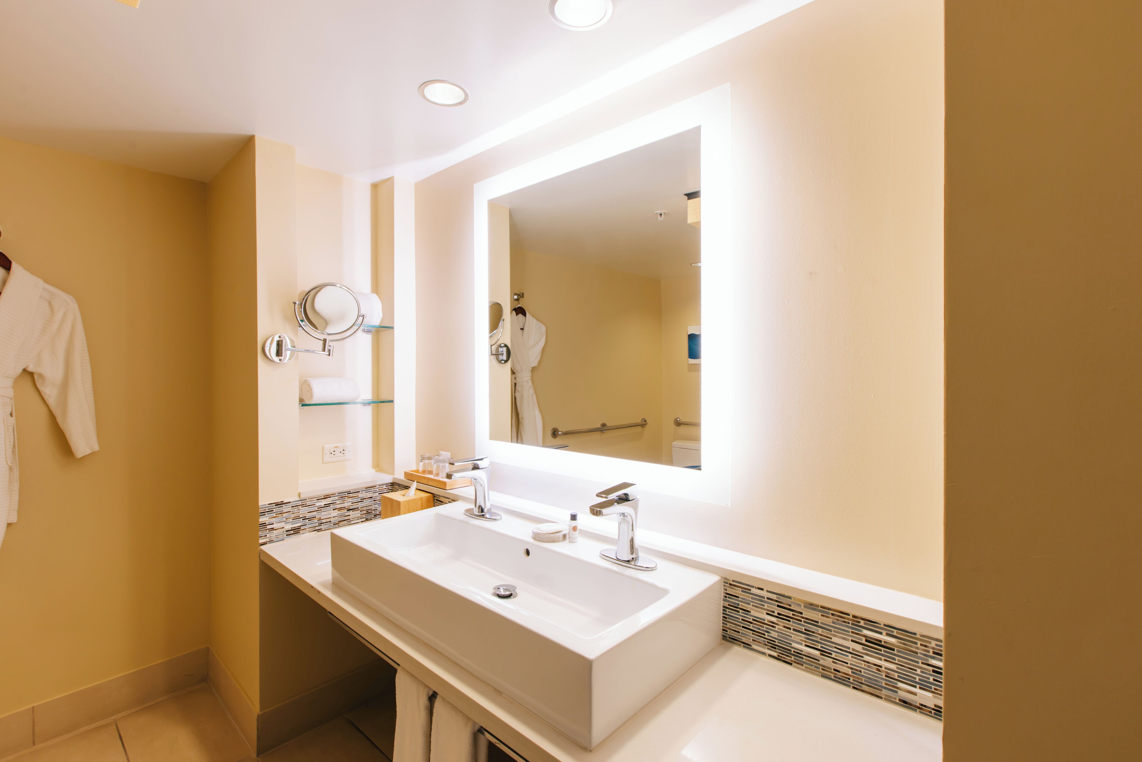 A modern bathroom with a large white sink, a mirror, and a towel rack.
