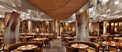 Un restaurante moderno con mesas redondas y asientos de cuero, que cuenta con un techo de madera y diseños abstractos en las paredes.