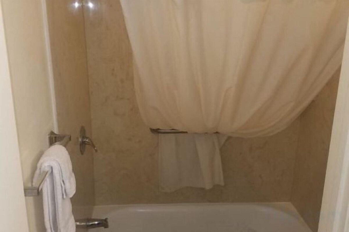A bathroom with a bathtub, a shower, and a towel rack.