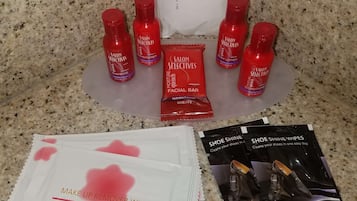 A countertop with various personal care items including shampoo, conditioner, body lotion, and makeup remover wipes.