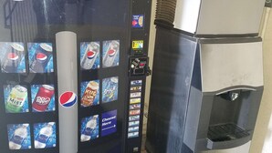 Un distributeur automatique orné du logo Pepsi et proposant une variété de boissons, notamment du Dr. Pepper et de l’eau Aquafina.
