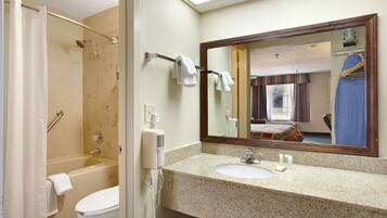A bathroom with a shower, toilet, sink, and a large mirror.