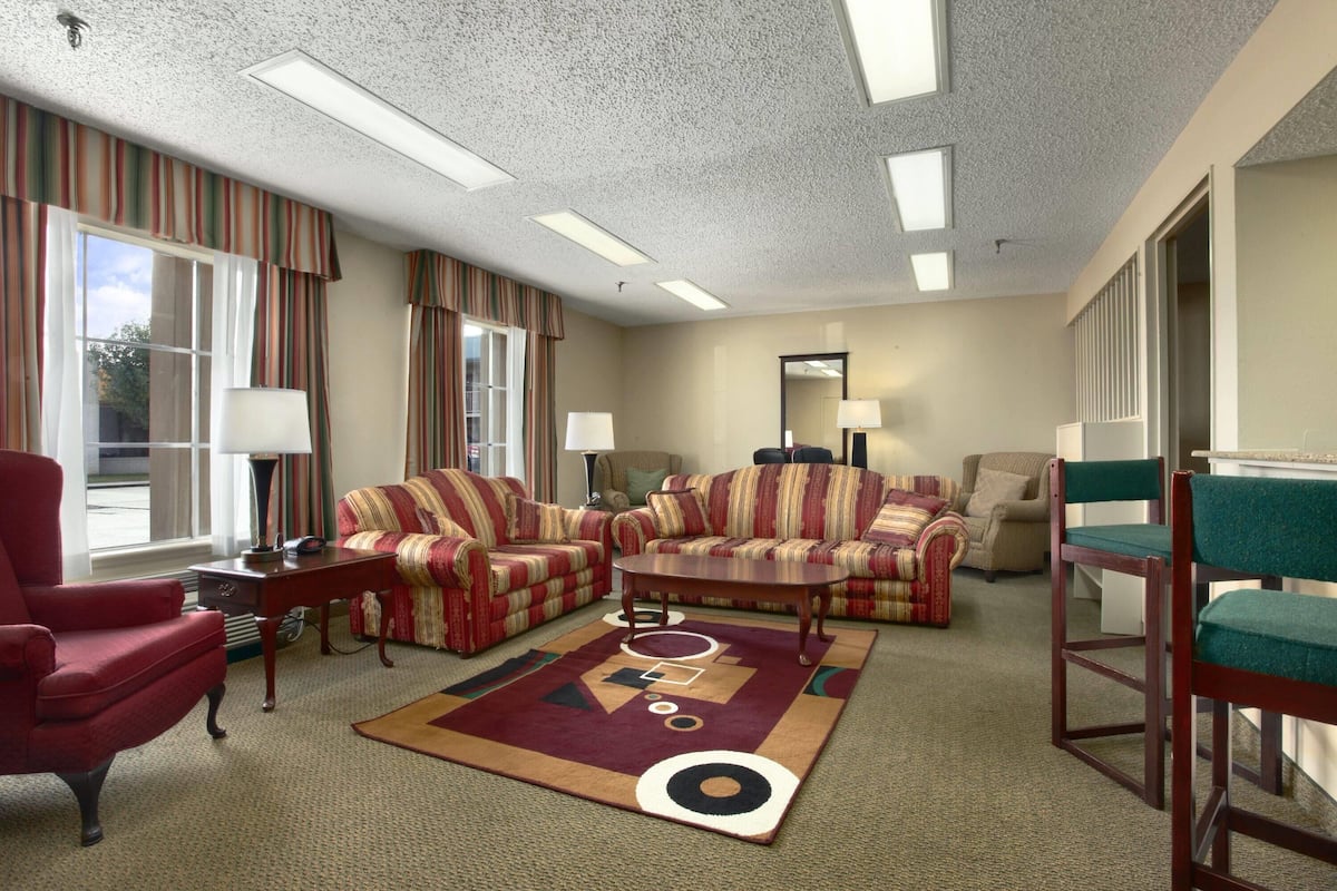 A hotel room with striped sofas, a red armchair, a coffee table, and a patterned rug.