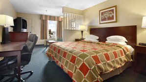 Une chambre d’hôtel équipée d’un lit, d’un bureau, d’une chaise et d’un téléviseur posé sur un meuble.