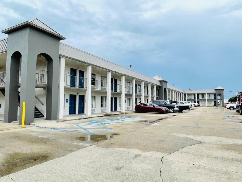 Un motel avec une série de chambres, un parking et une allée couverte.