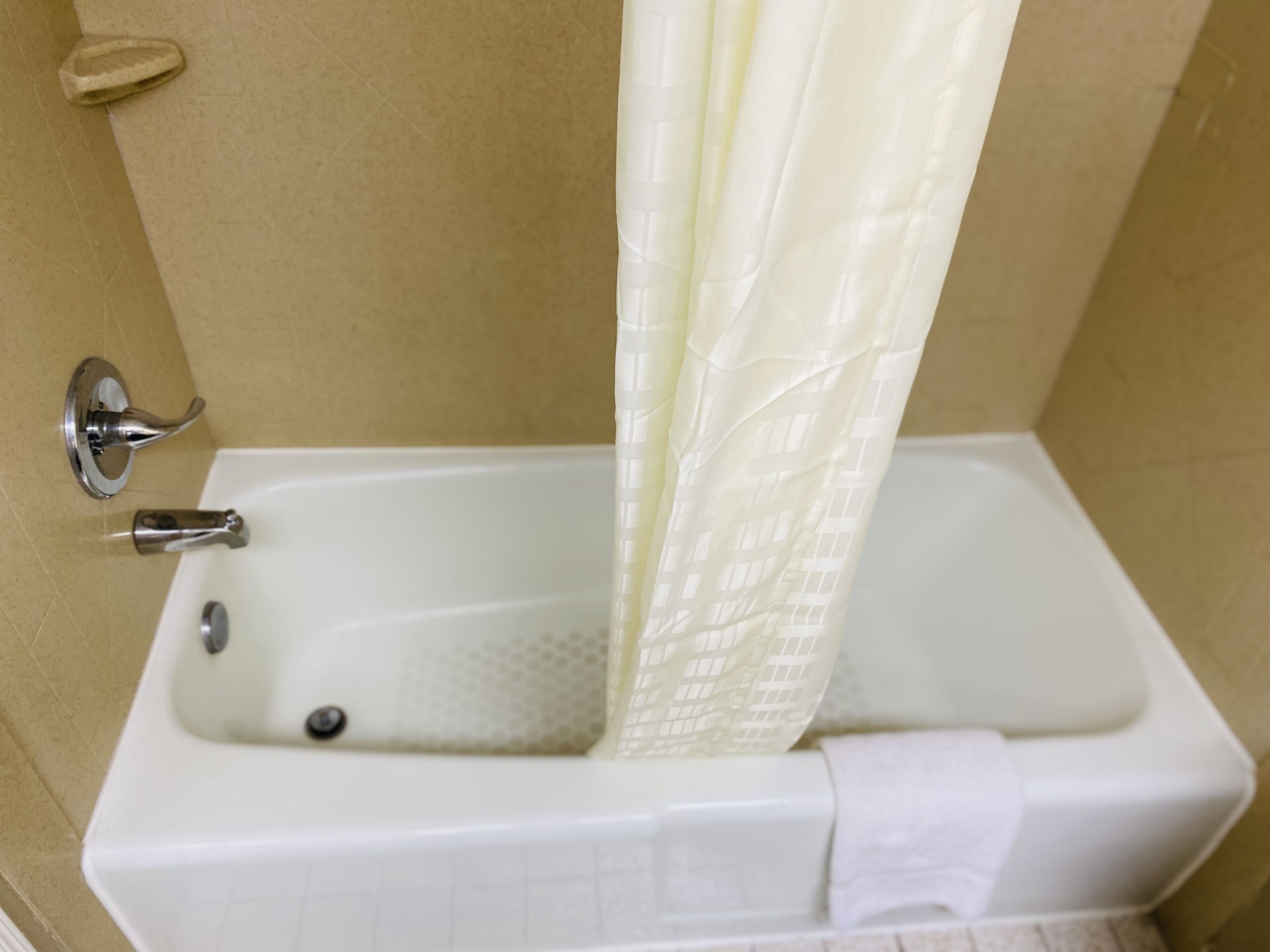 Une baignoire avec un rideau de douche, un robinet et une serviette.