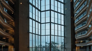 A multi-level hotel interior with a central atrium, multiple balconies, and a view of the outdoors. - Torre Melina, a Gran Meliá Hotel (Barcelona)