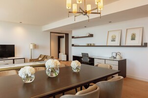 Un salon moderne comprenant une table à manger, des canapés, un téléviseur et un lustre.