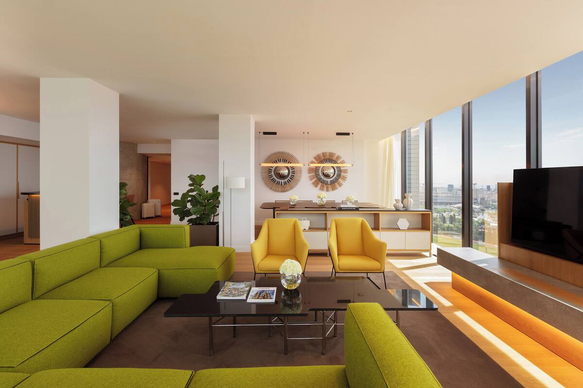 Una sala de estar moderna con un sofá seccional, sillones amarillos, una mesa de centro y una pantalla de televisión grande.