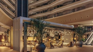 A modern hotel lobby with multiple floors, a central seating area with sofas and tables, and a large plant in the middle. - Torre Melina, a Gran Meliá Hotel (Barcelona)