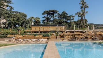 A pool area with lounge chairs, a bar, and tropical vegetation.