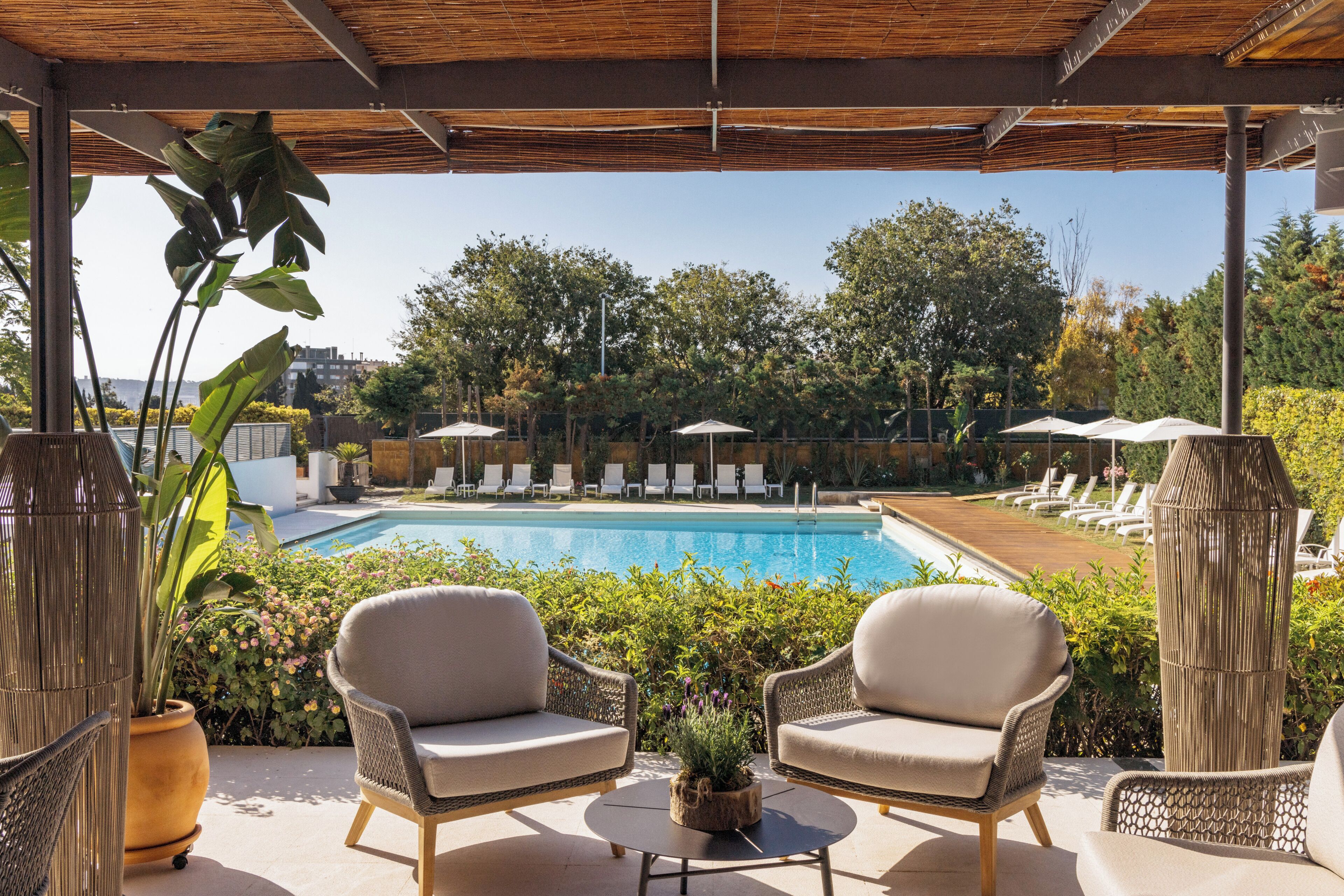 A poolside area with wicker chairs, a small table, and umbrellas.
