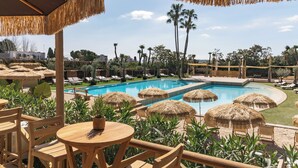 A poolside area with thatched umbrellas, lounge chairs, and a view of the pool. - Torre Melina, a Gran Meliá Hotel (Barcelona)