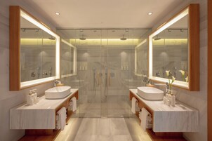 A modern bathroom with two sinks, a glass shower enclosure, and large mirrors.