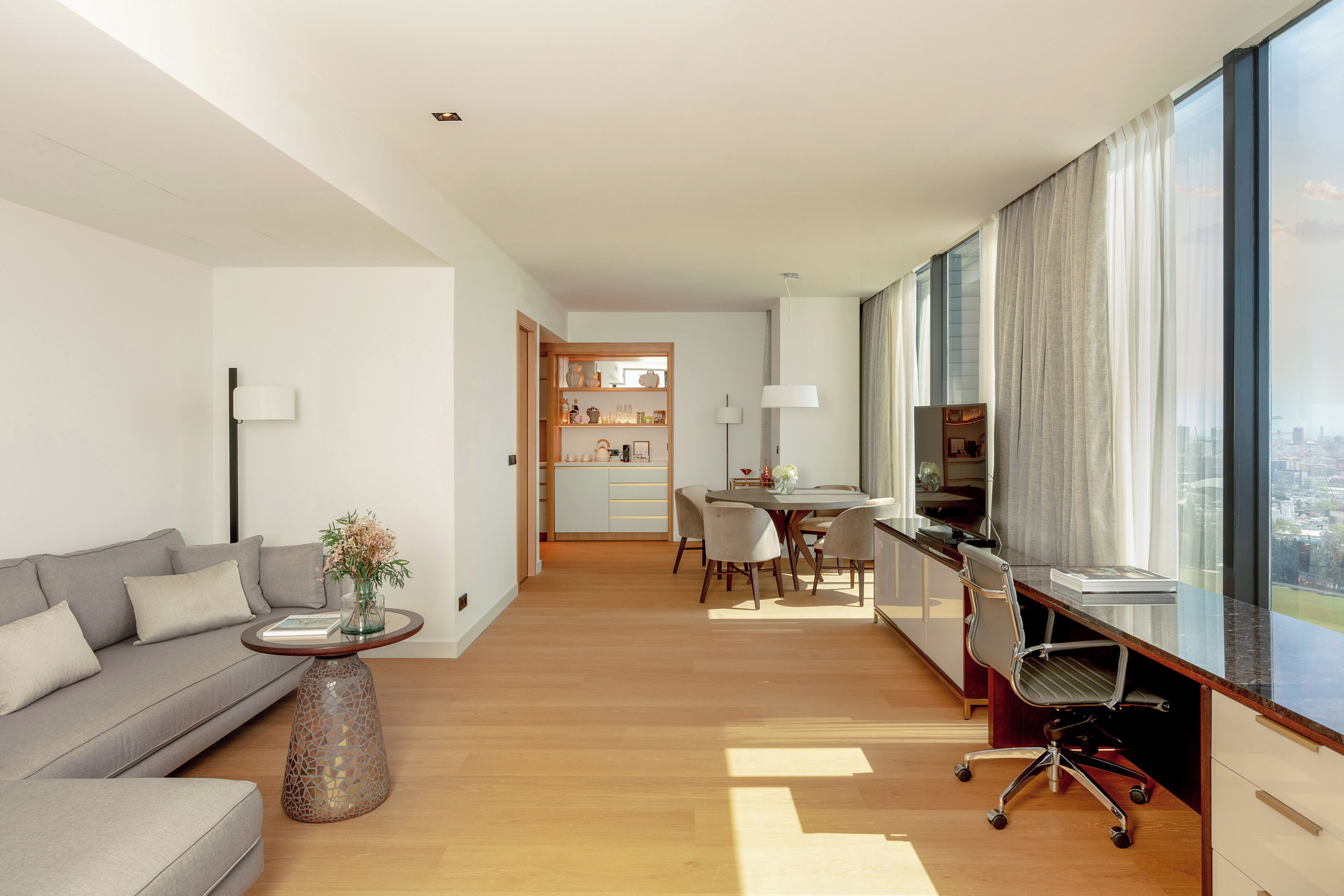Un salon moderne comprenant un canapé, une table basse et un coin repas avec des chaises et une table.