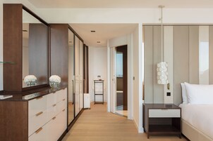 A hotel room with a wooden dresser, a bed with white linens, a nightstand, and a mirror.
