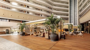 A multi-level hotel lobby with a central seating area, large potted plants, and a high ceiling. - Torre Melina, a Gran Meliá Hotel (Barcelona)