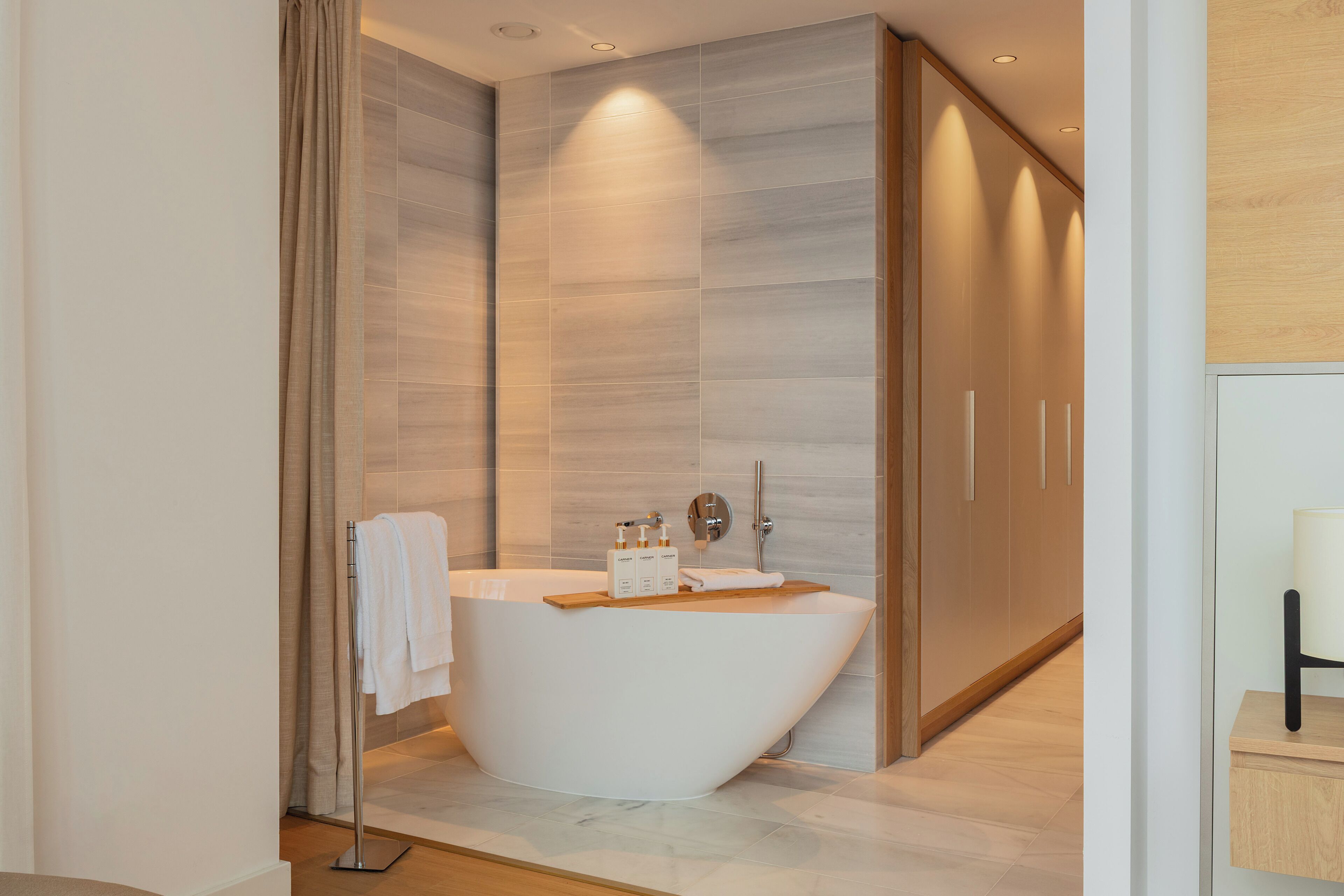 Un baño moderno con una bañera independiente, un perchero y un tocador de madera.