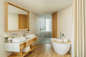A modern bathroom with two sinks, a large mirror, and a walk-in shower.
