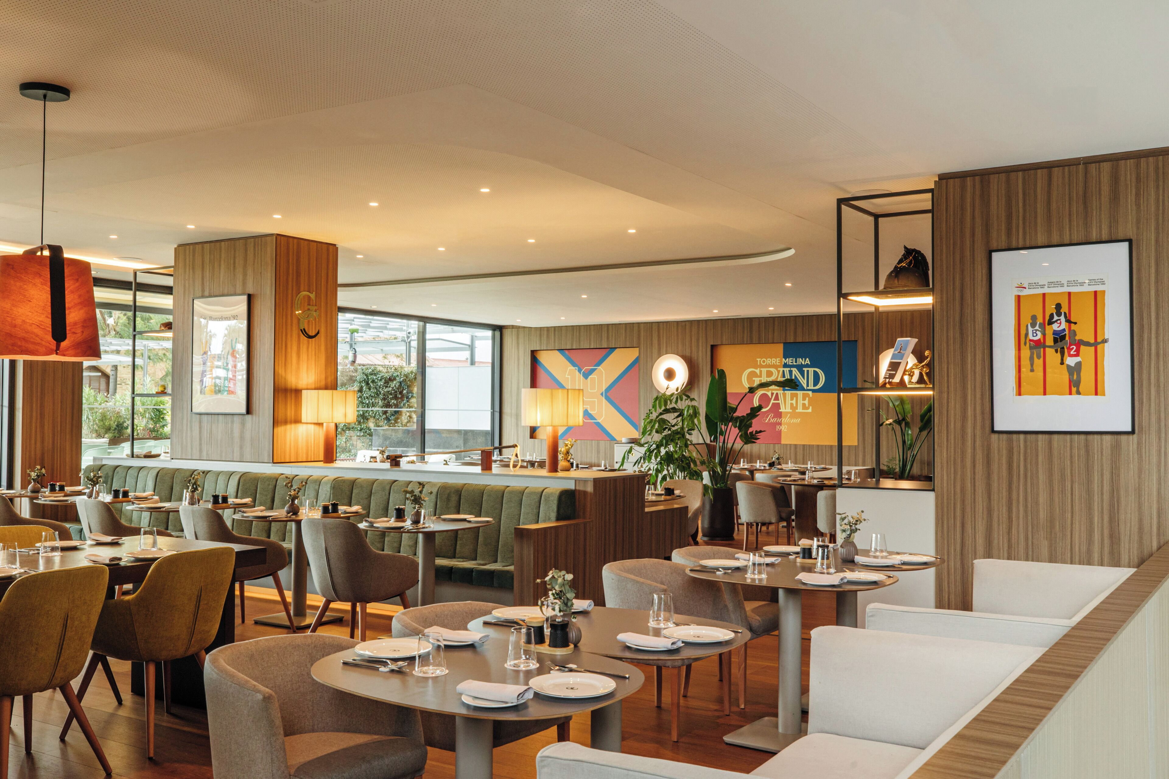 Un ristorante moderno con tavoli rotondi, sedute rivestite in verde e un'area bar.