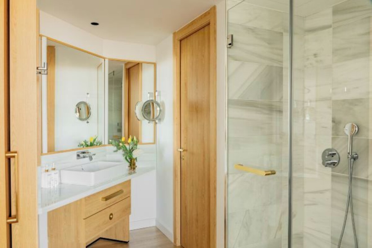 Une salle de bain moderne avec une douche à parois de verre, des meubles en bois et un grand miroir.