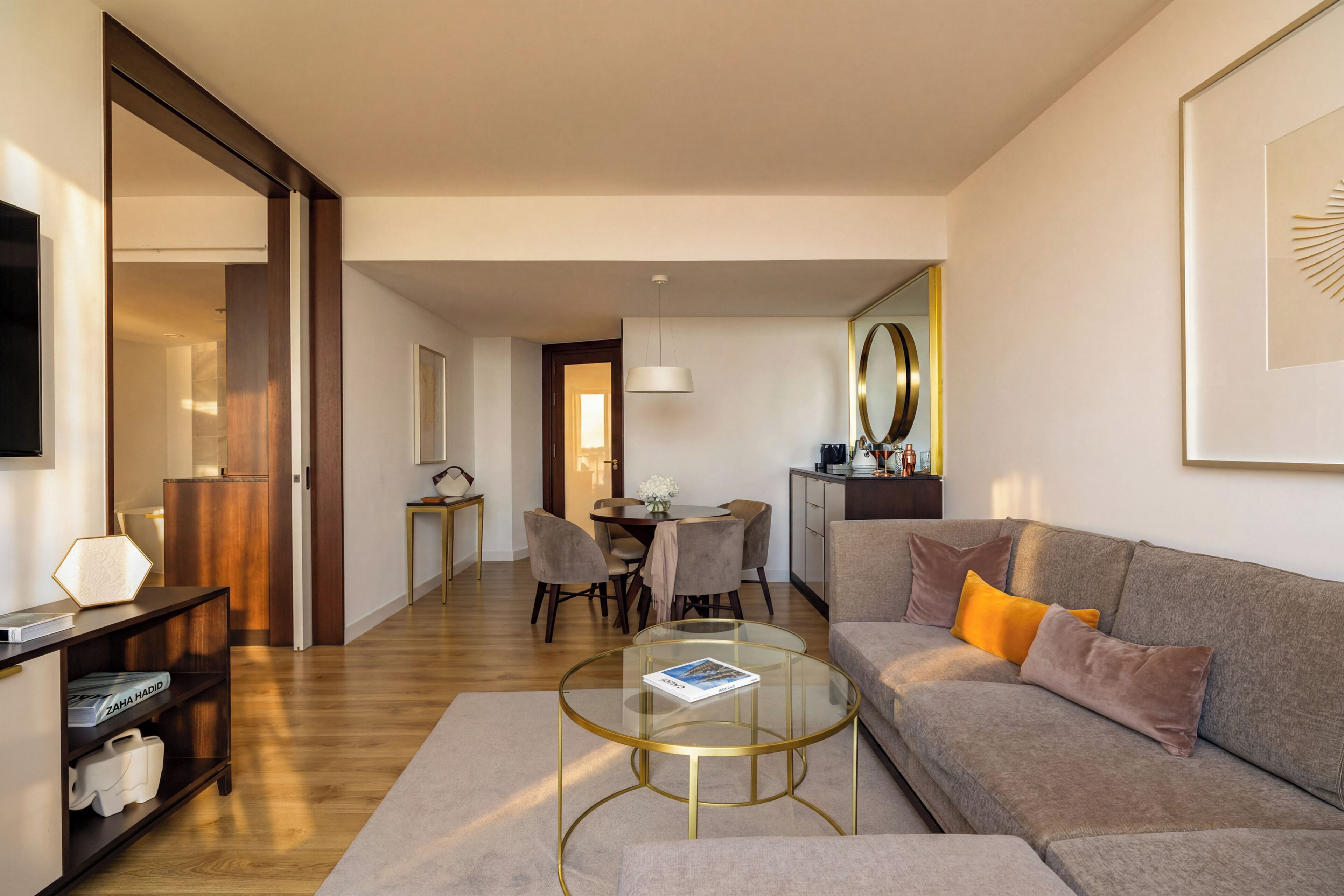 A modern living room with a sofa, coffee table, and a dining area with chairs.